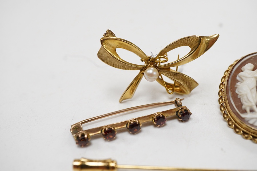 A collection 9ct brooches to include a shell cameo carved with the Three Graces, an amethyst set floral spray brooch, a cultured pearl set ribbon brooch, a garnet set bar brooch and a cultured pearl set stick pin, togeth